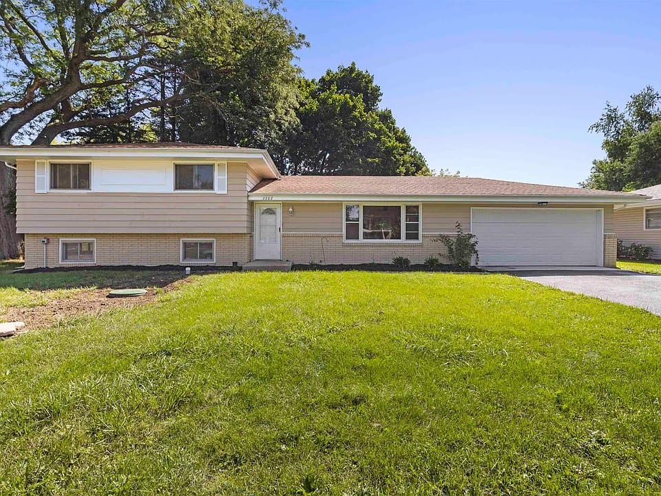 A beige split-level home with a brick lower course, an attached garage and the number 2202 on the front fascia.